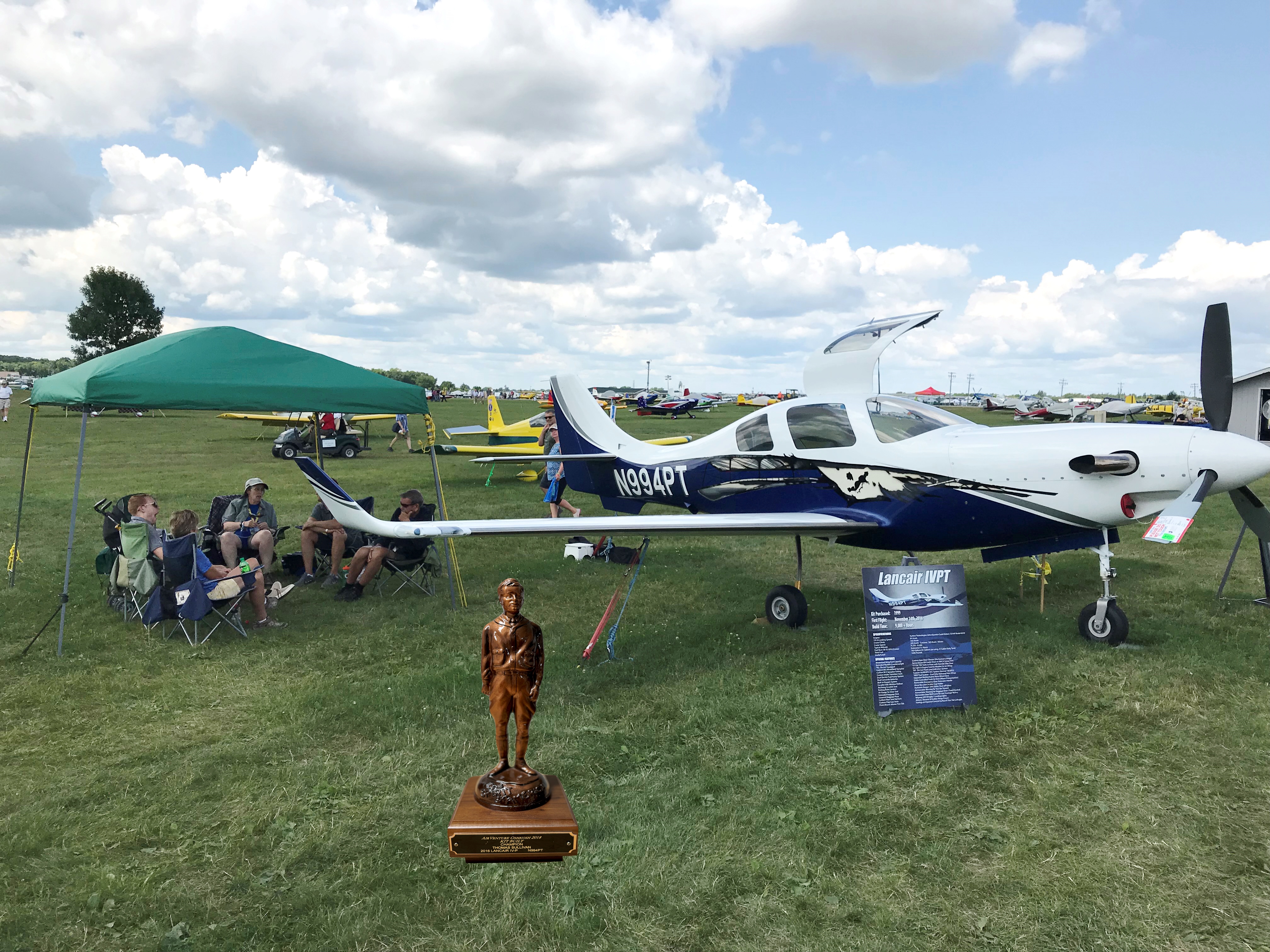 Picture from my Oshkosh judged year with my family and friends with me under the tent and the Lindy placed in the picture for motivation during my rebuild.  It’s been placed in a 3’ x 4’ picture frame in the garage where we are rebuilding the plane.