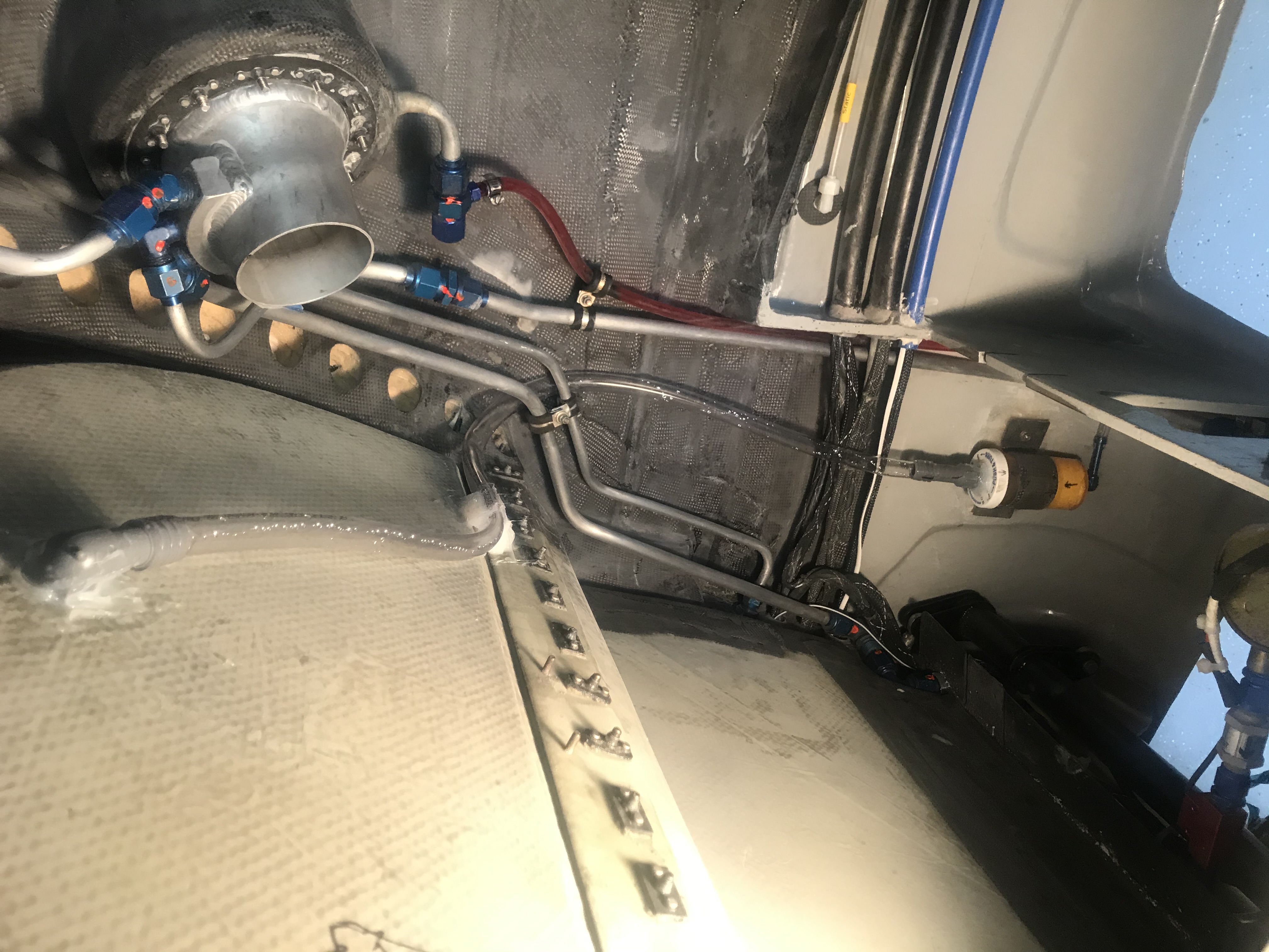 Fuel filler for the baggage fuel tank.  Also note the condensate drain line for the A/C coming through the pressure bulkhead with the hose running to a special drain valve (home made) that only allows drainage when water is present, otherwise sealing for cabin pressurization.